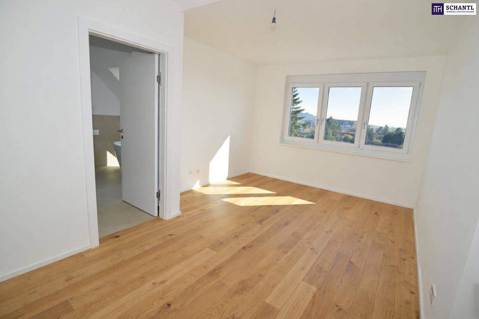 Helles Schlafzimmer mit Holzboden und Fenster mit Blick ins Grüne.