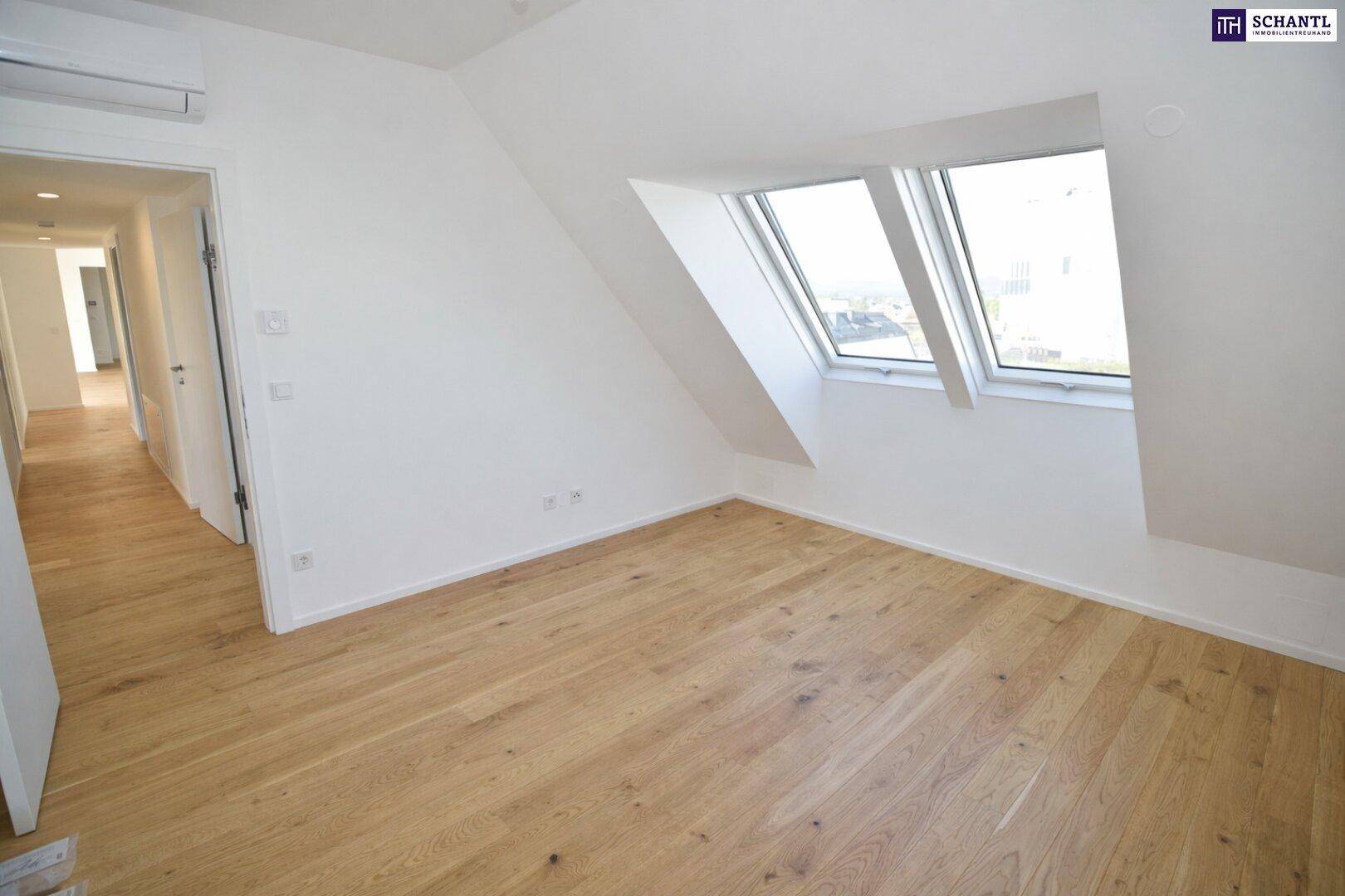 Helles Schlafzimmer mit Holzboden und Dachfenstern in einem Neubau.