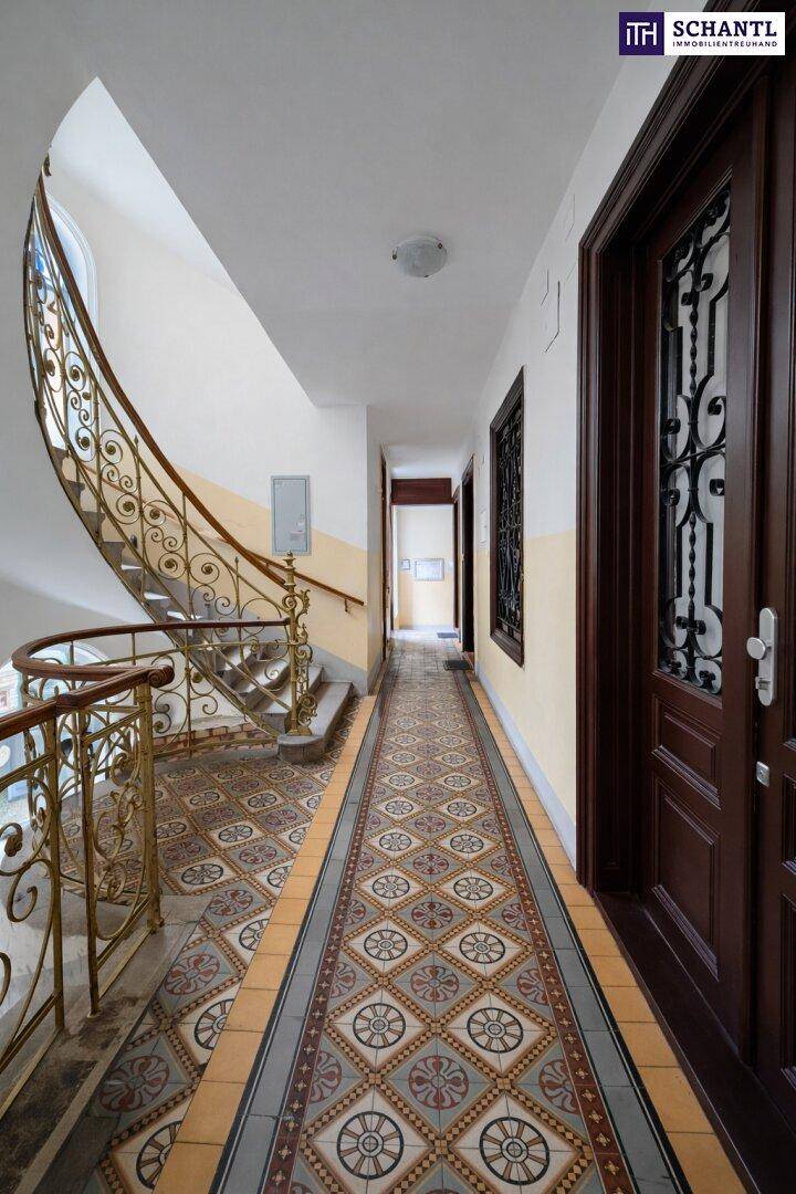 Elegantes Treppenhaus mit kunstvollem Geländer und gemusterten Fliesen, typisch für Altbau.