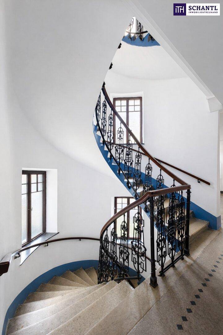 Elegantes, geschwungenes Treppenhaus mit schmiedeeisernem Geländer und blauen Akzenten.