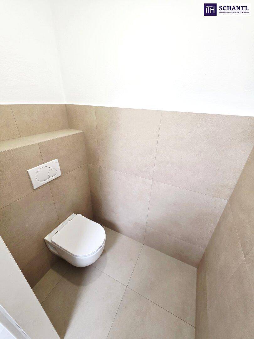 Kleines Gäste-WC mit Wand-WC und hellen, beigefarbenen Fliesen an Wänden und Boden.