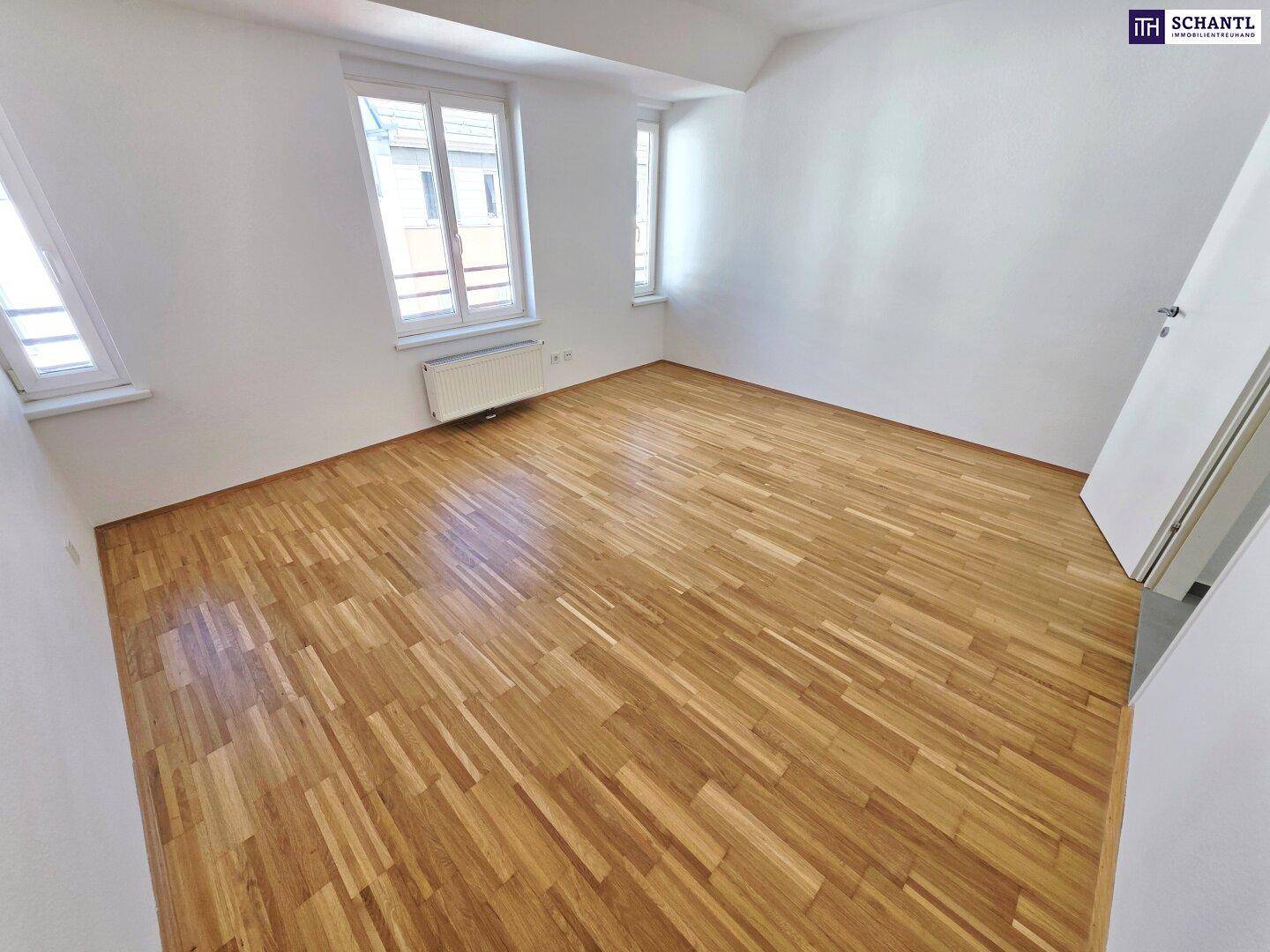 Helles Schlafzimmer mit Parkettboden und mehreren Fenstern, die viel Tageslicht hereinlassen.