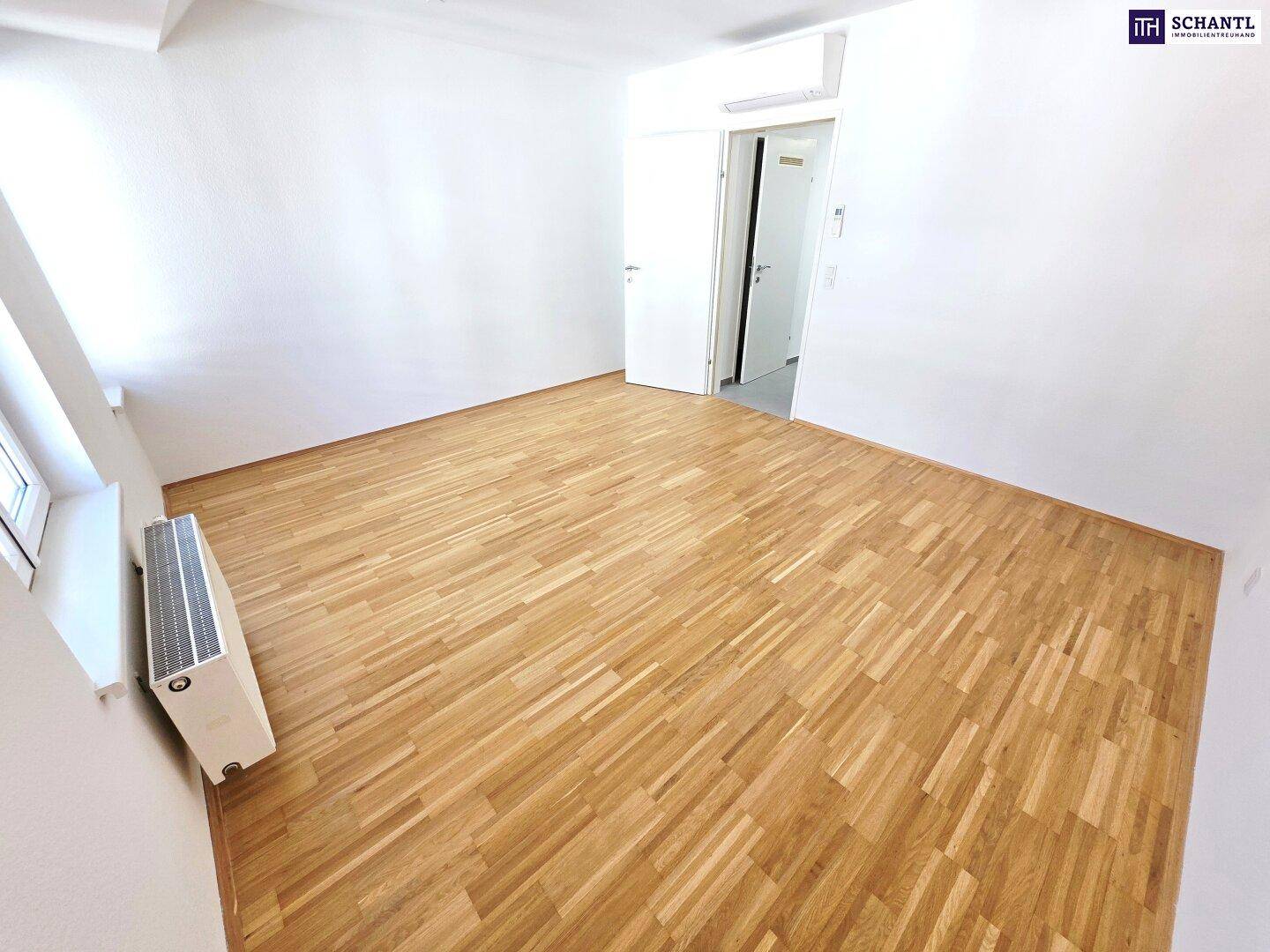 Geräumiges Schlafzimmer mit Holzboden und Heizkörper unter dem Fenster, bereit zur Einrichtung.