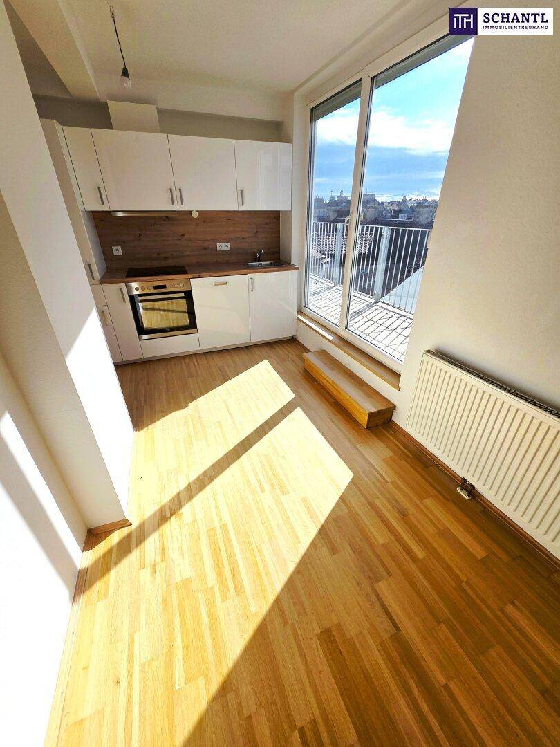 Kompakte Küchenzeile mit Holzarbeitsplatte, Induktionskochfeld und Zugang zu einem Balkon.
