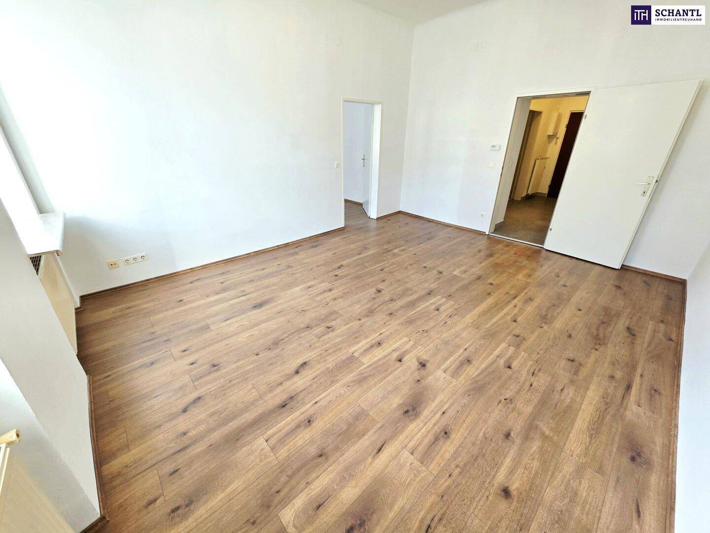 Geräumiges, helles Zimmer mit Laminatboden und weißen Wänden, ideal für Wohn- oder Schlafbereich.