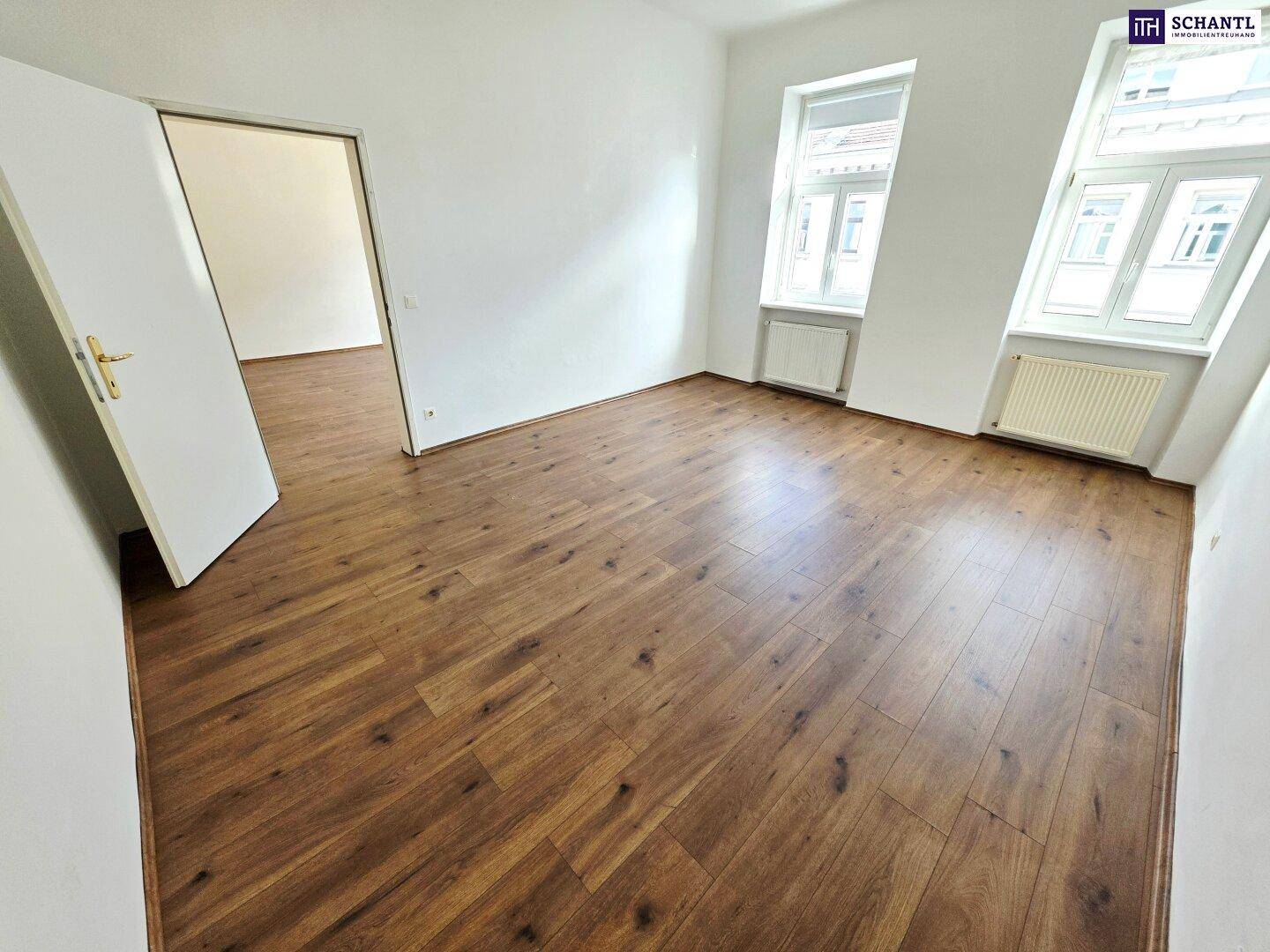Helles Zimmer mit Laminatboden und weißen Wänden, bietet viel Potenzial für individuelle Einrichtung.