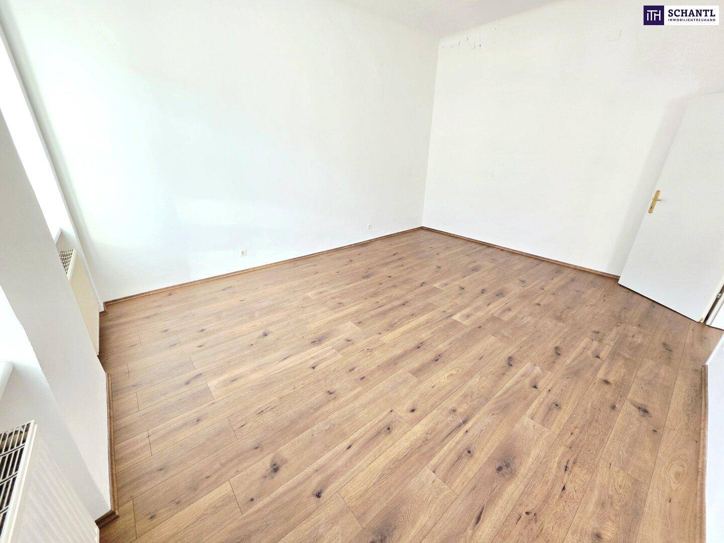 Helles Zimmer mit Laminatboden und weißen Wänden, bietet viel Potenzial für individuelle Einrichtung.
