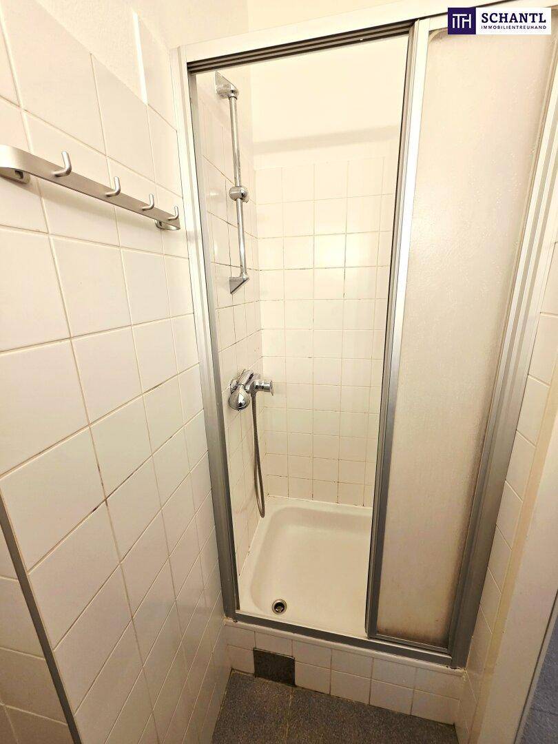 Funktionale Duschkabine mit weißen Fliesen und Glasschiebetür in einem Badezimmer.