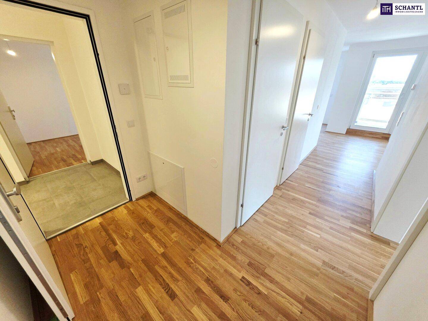 Heller Eingangsbereich einer Wohnung mit Parkettboden und weißen Türen.