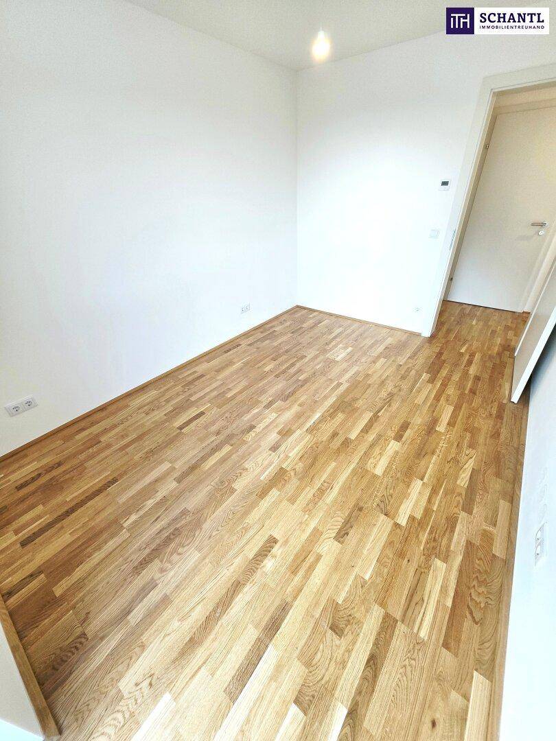 Leeres Zimmer mit hellem Parkettboden und weißen Wänden, ideal als Schlaf- oder Arbeitszimmer.