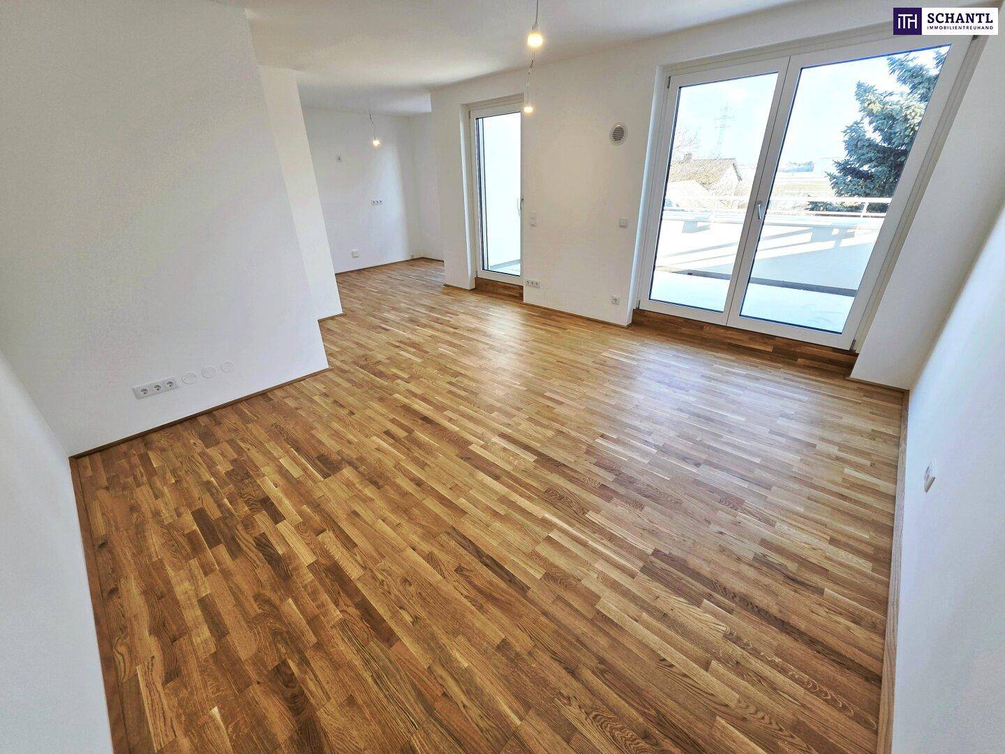 Lichtdurchfluteter Wohnbereich mit Parkettboden und großen Fenstern, die viel Tageslicht hereinlassen.