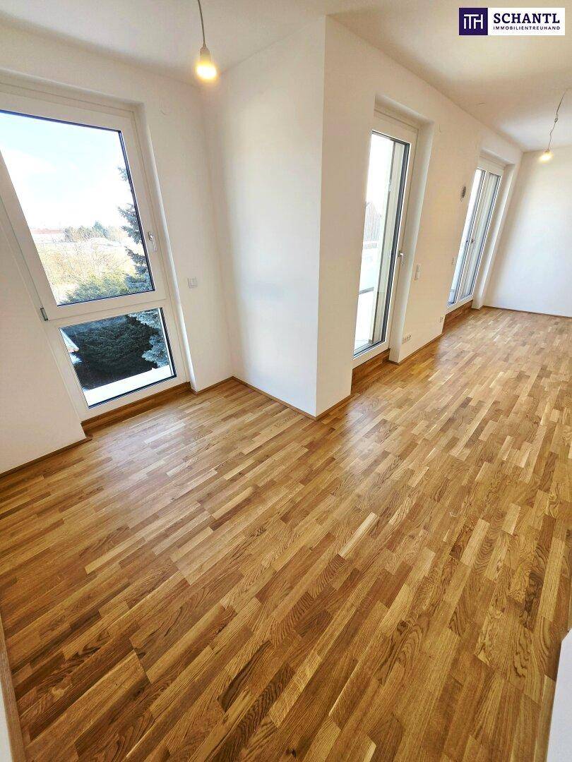 Geräumiger, heller Raum mit Parkettboden und großen Fenstern, die viel Licht spenden.
