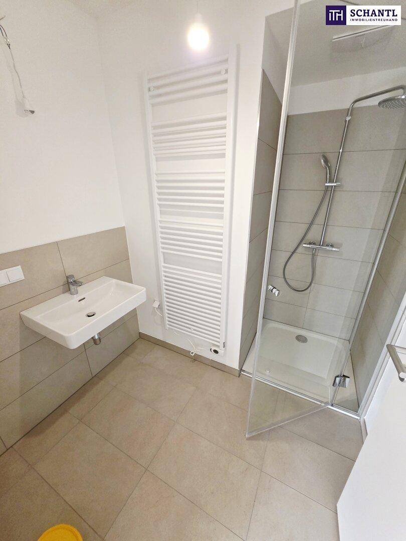 Modernes Badezimmer mit Dusche, Waschbecken und beheiztem Handtuchhalter.