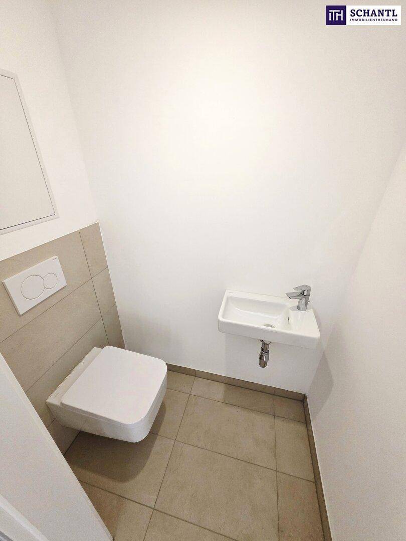 Modernes Gäste-WC mit wandhängender Toilette und kleinem Waschbecken.