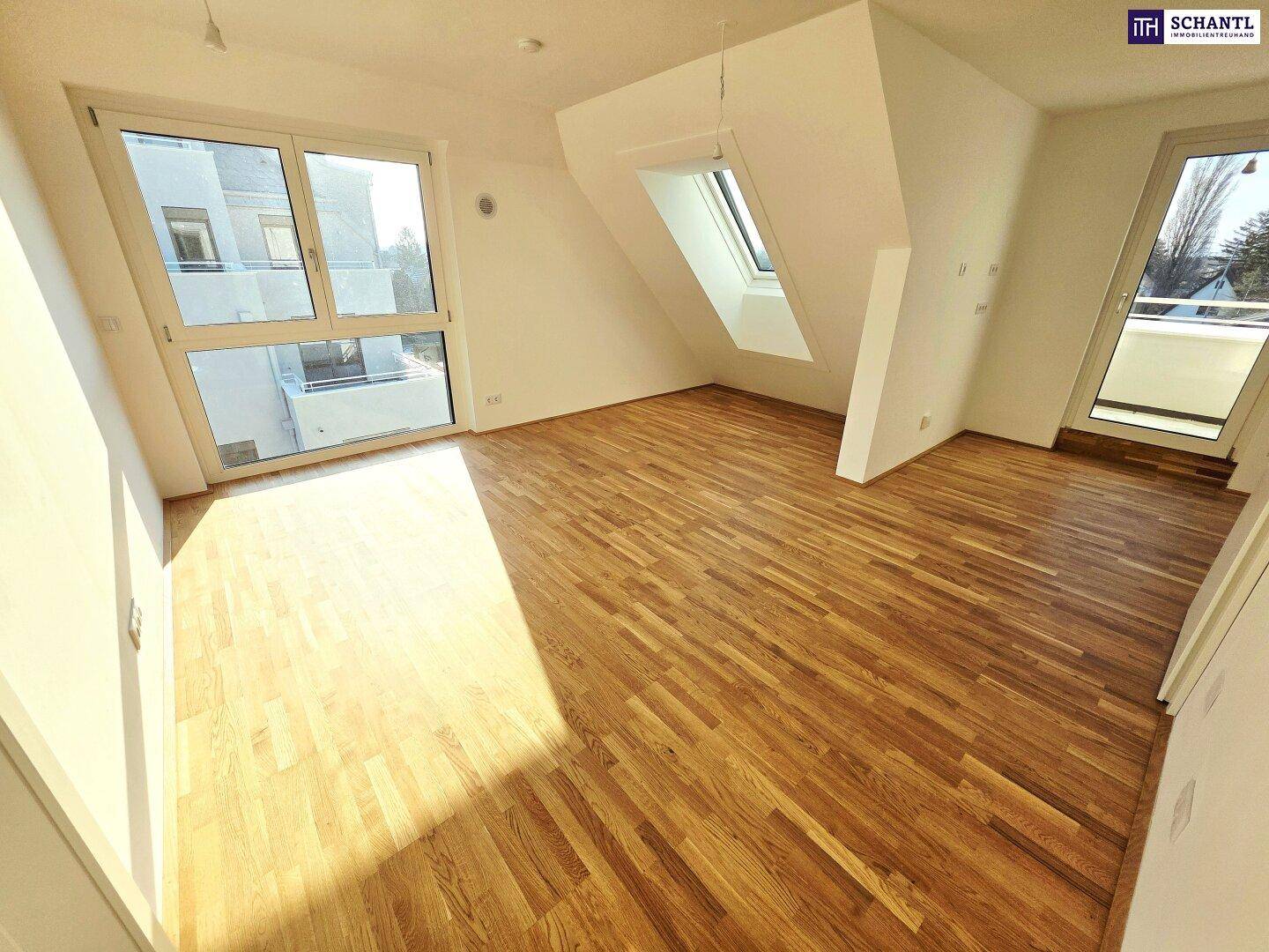 Lichtdurchfluteter Raum mit Holzboden, großen Fenstern und Zugang zu einem Balkon.