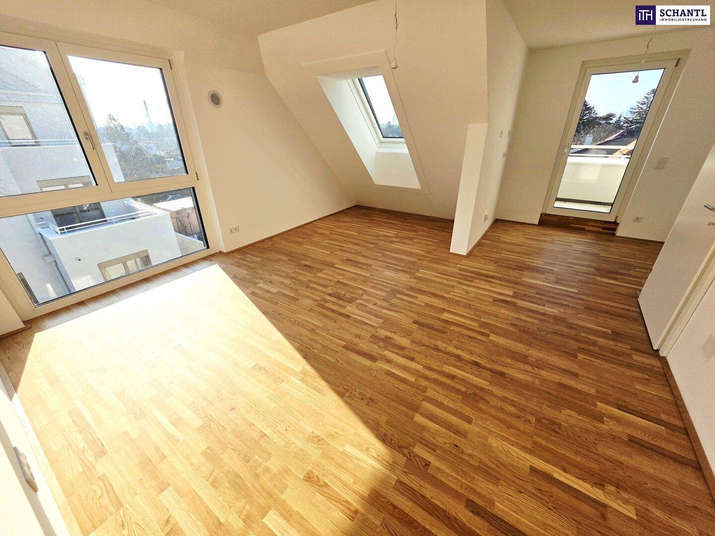 Geräumiger, heller Raum mit Holzboden, großen Fenstern und Zugang zum Balkon.