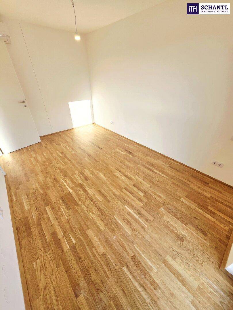 Helles Zimmer mit Holzboden und Fenster, geeignet als Schlafzimmer oder Arbeitsbereich.