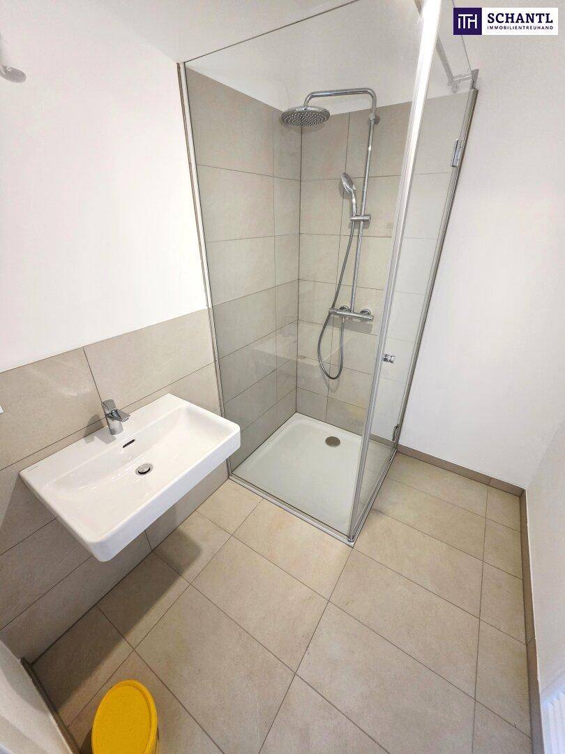 Modernes Badezimmer mit Duschkabine, Waschbecken und hellen Fliesen, minimalistisches Design.