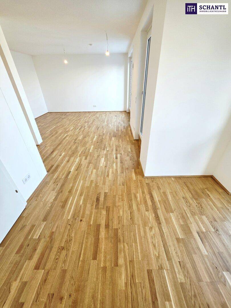 Lichtdurchfluteter Wohnbereich mit hellem Parkettboden und großen Fenstern, ideal für individuelle Gestaltung.