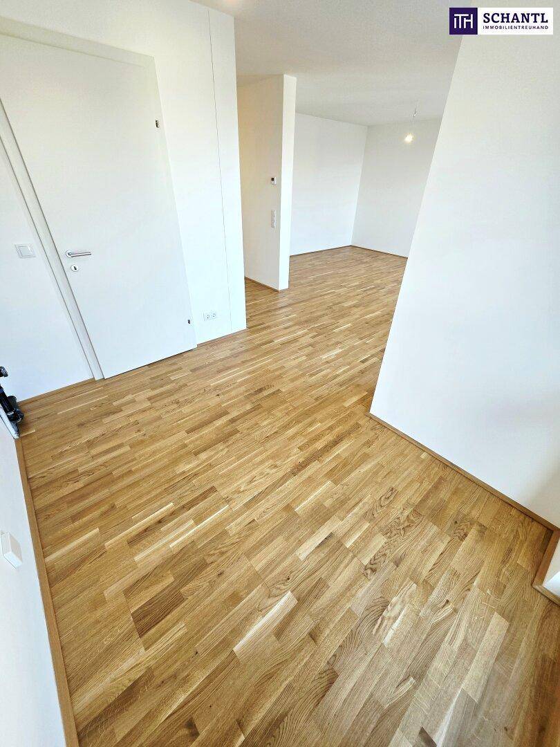 Geräumiger, heller Wohnbereich mit Parkettboden und weißen Wänden, bietet viel Gestaltungsfreiheit.