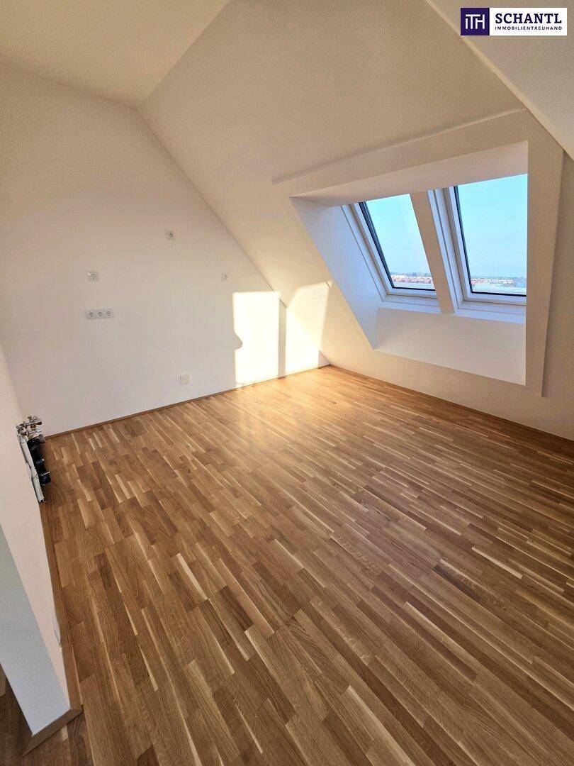 Geräumiges Zimmer im Dachgeschoss mit Holzboden und schrägen Wänden, beleuchtet durch Dachfenster.