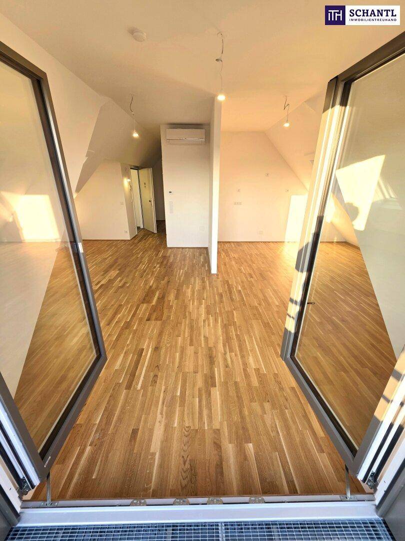 Heller, leerer Raum im Dachgeschoss mit Holzboden und Zugang zu einem französischen Balkon.