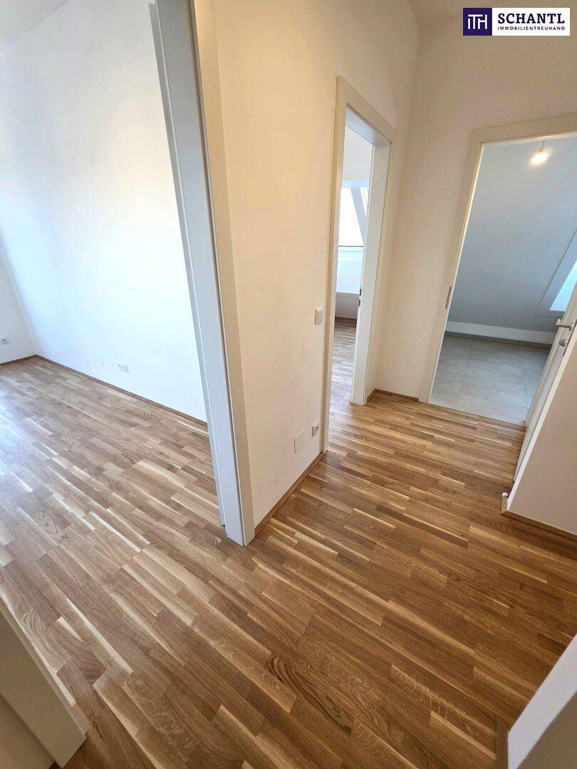 Heller Flur mit Holzboden, der zu verschiedenen Zimmern im Dachgeschoss führt.