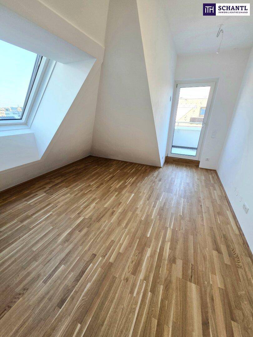 Helles Zimmer im Dachgeschoss mit Holzboden und Zugang zu einem Balkon, zusätzlich mit Dachfenstern.