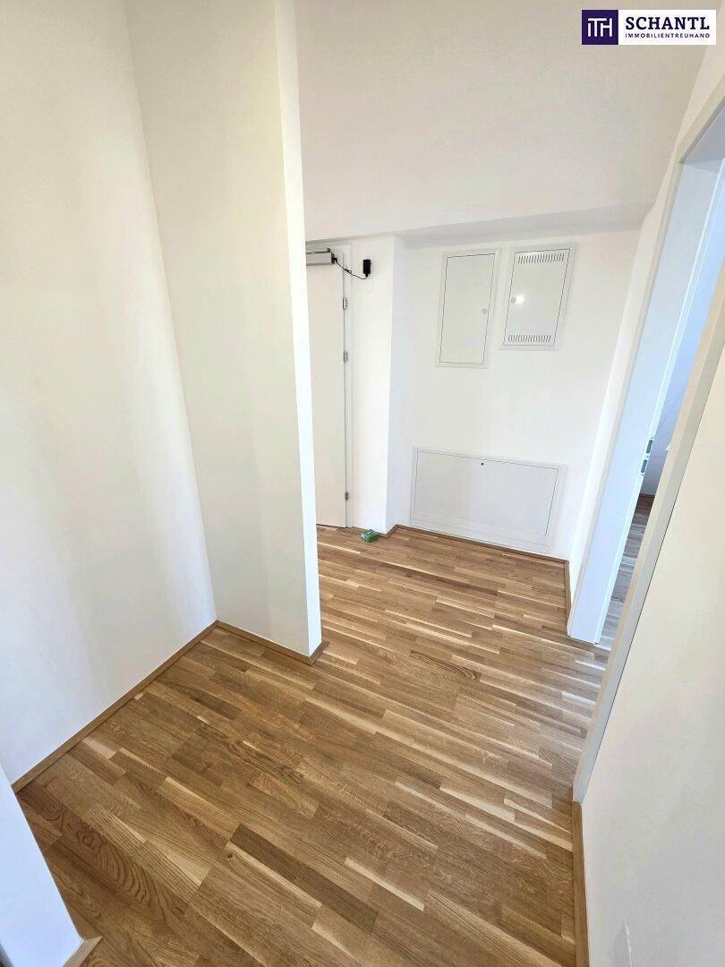 Eingangsbereich mit Holzboden und weißen Wänden, der Zugang zu verschiedenen Bereichen bietet.