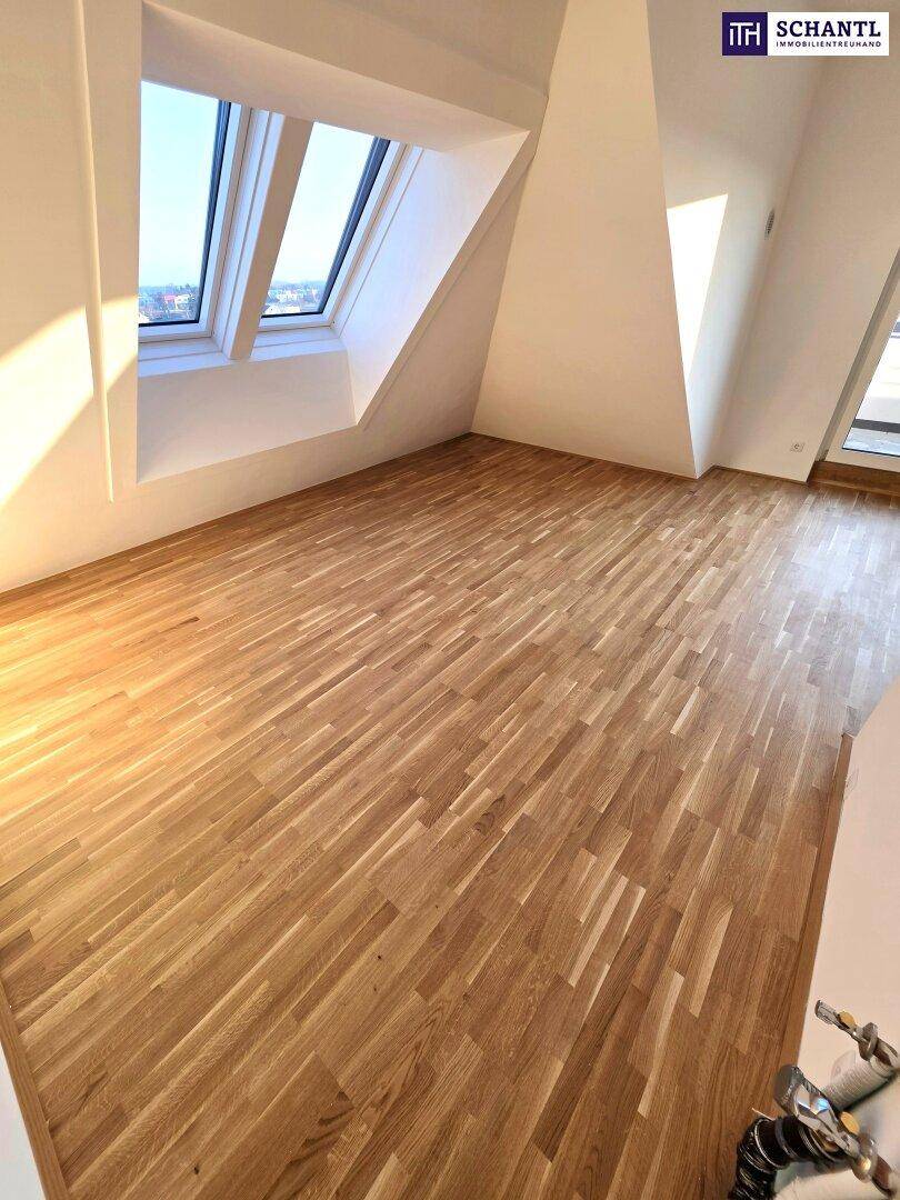 Großes Zimmer im Dachgeschoss mit Holzboden und schrägen Wänden, hell durch Dachfenster.