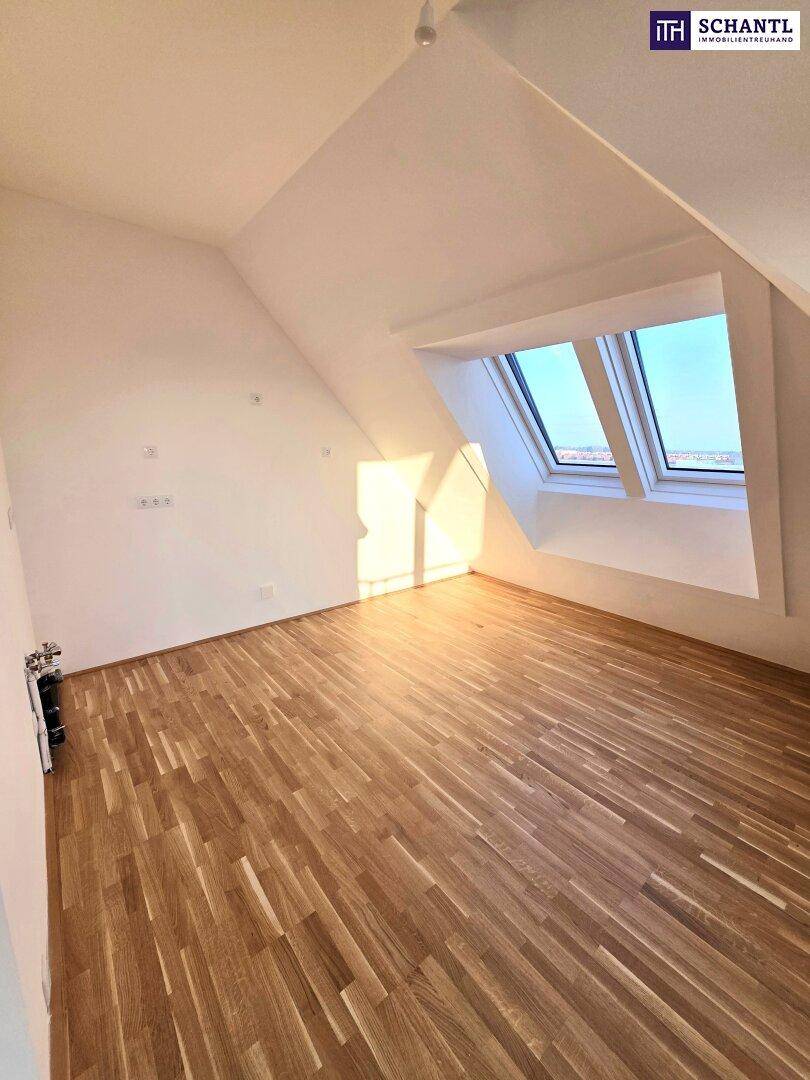 Helles Schlafzimmer im Dachgeschoss mit Holzboden und großen Dachfenstern, die viel Licht hereinlassen.
