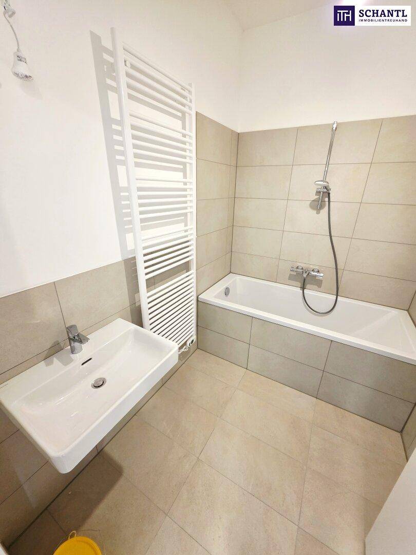 Modernes Badezimmer mit Badewanne, Waschbecken und beheiztem Handtuchhalter.