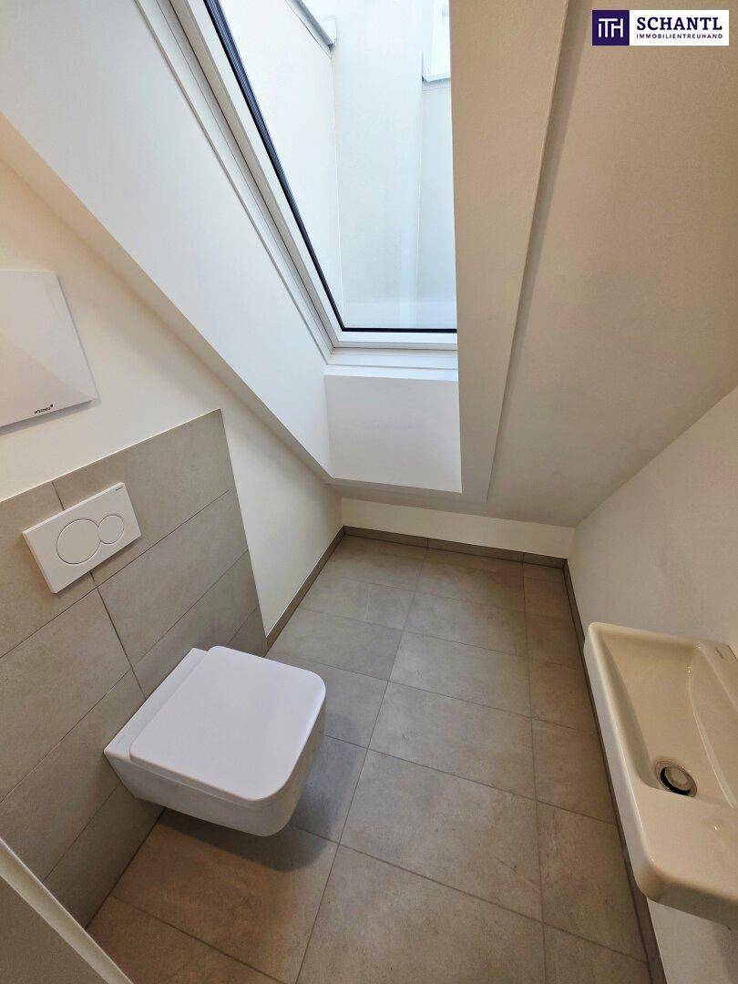 Modernes Gäste-WC mit wandhängender Toilette, Waschbecken und Dachfenster.