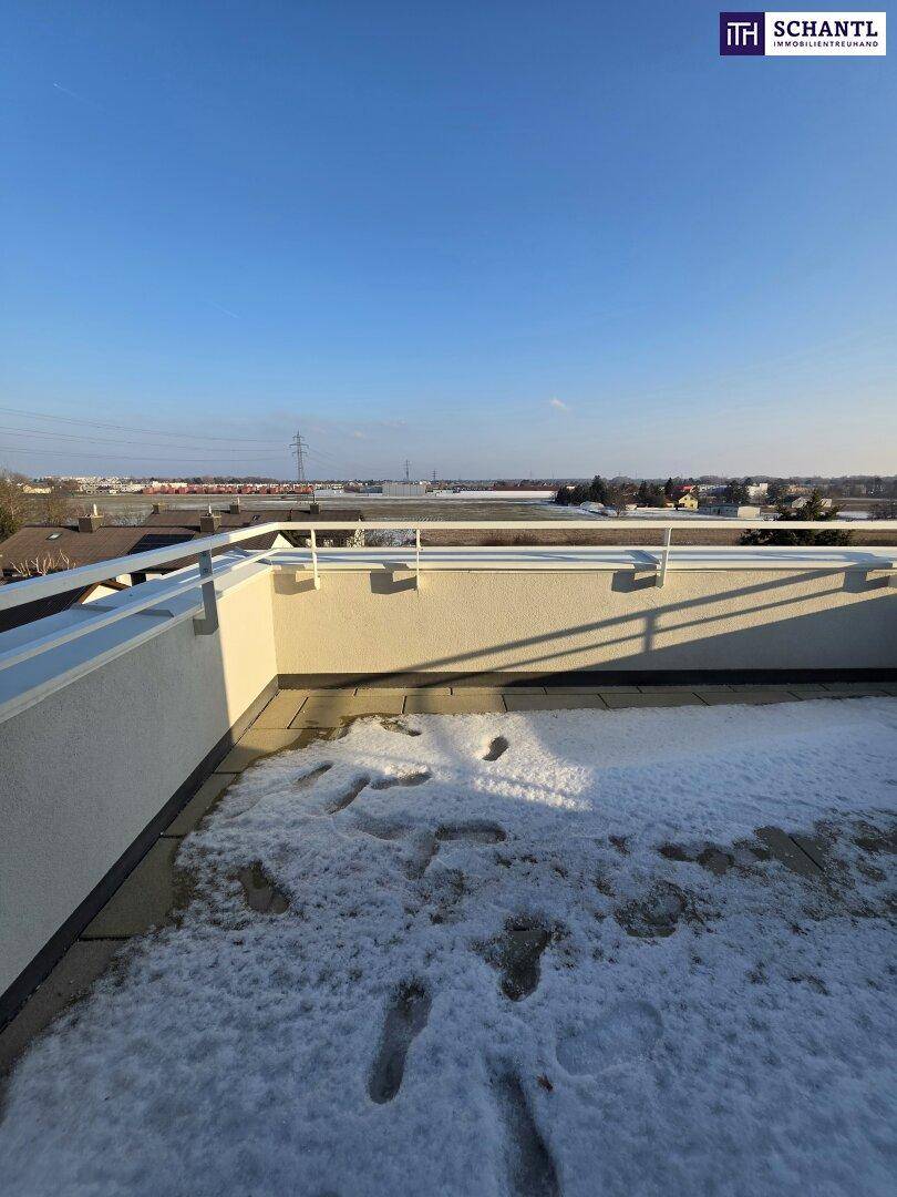 Dachterrasse mit weitem Blick über die Landschaft und Spuren im Schnee, sonniger Tag.