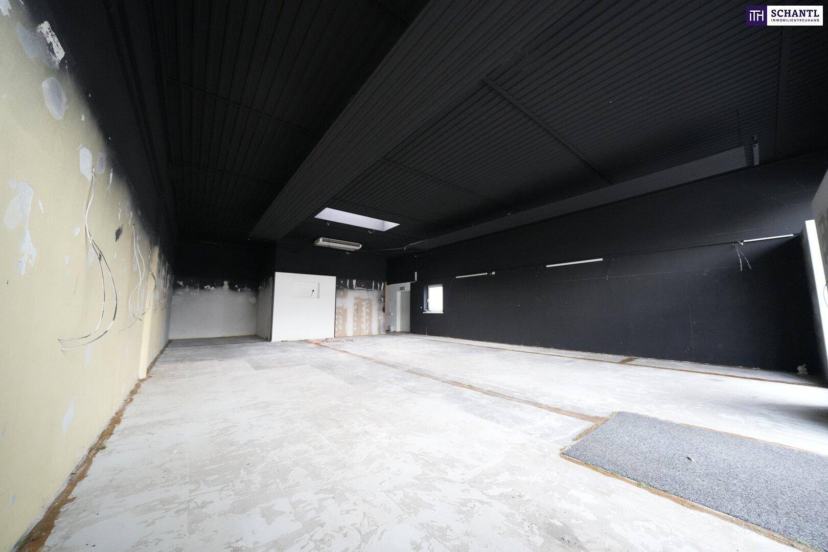 Geräumiger Gewerberaum mit schwarzer Decke, Betonboden und sichtbaren Installationen, ideal für individuelle Gestaltung.