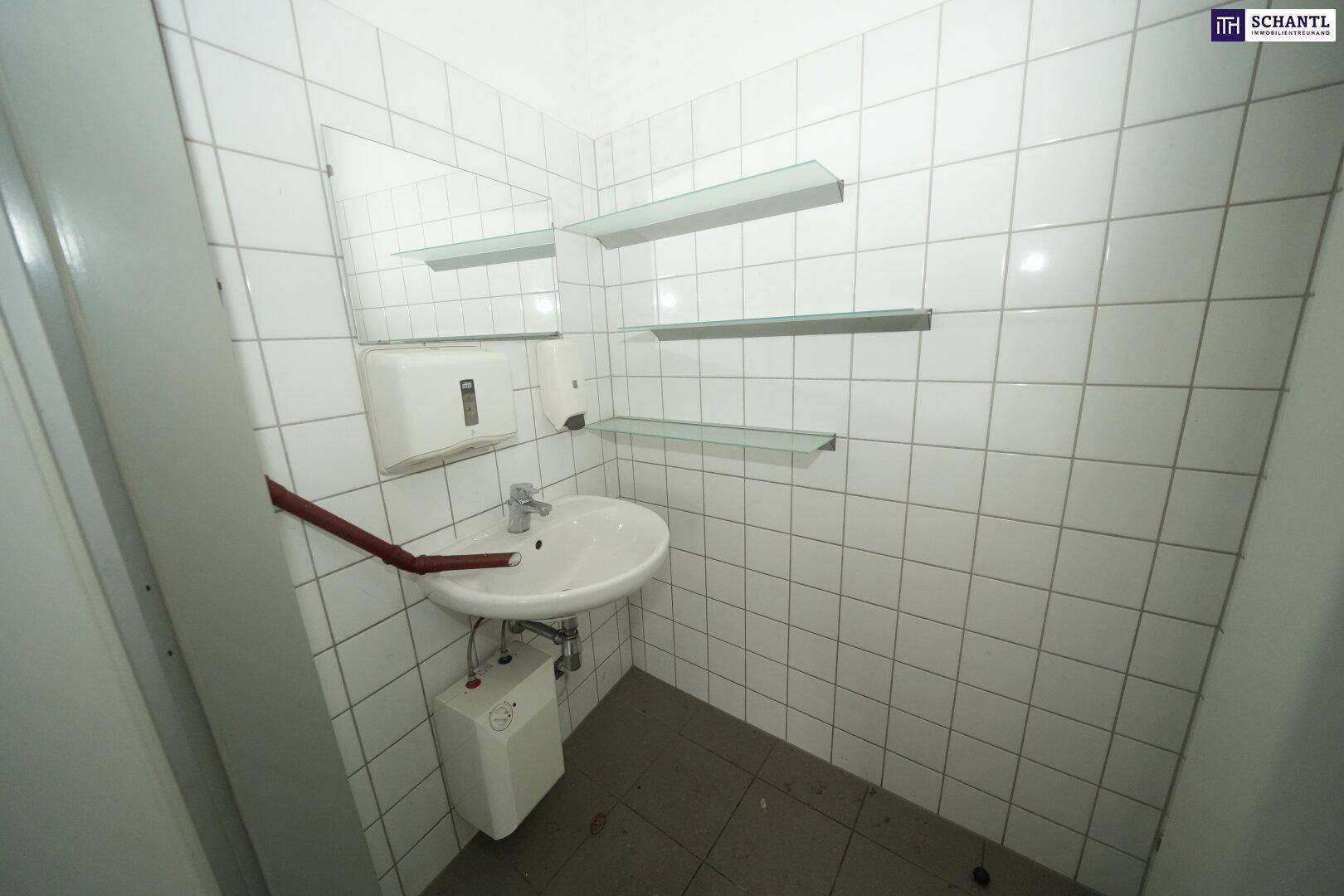 Kleines, gefliestes Badezimmer mit Waschbecken, Spiegel und Ablageflächen, ideal als Gästetoilette.
