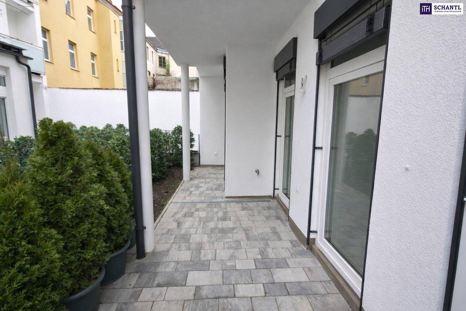 Überdachte Terrasse mit Pflastersteinen und Blick auf die umliegenden Gebäude und Grünflächen.