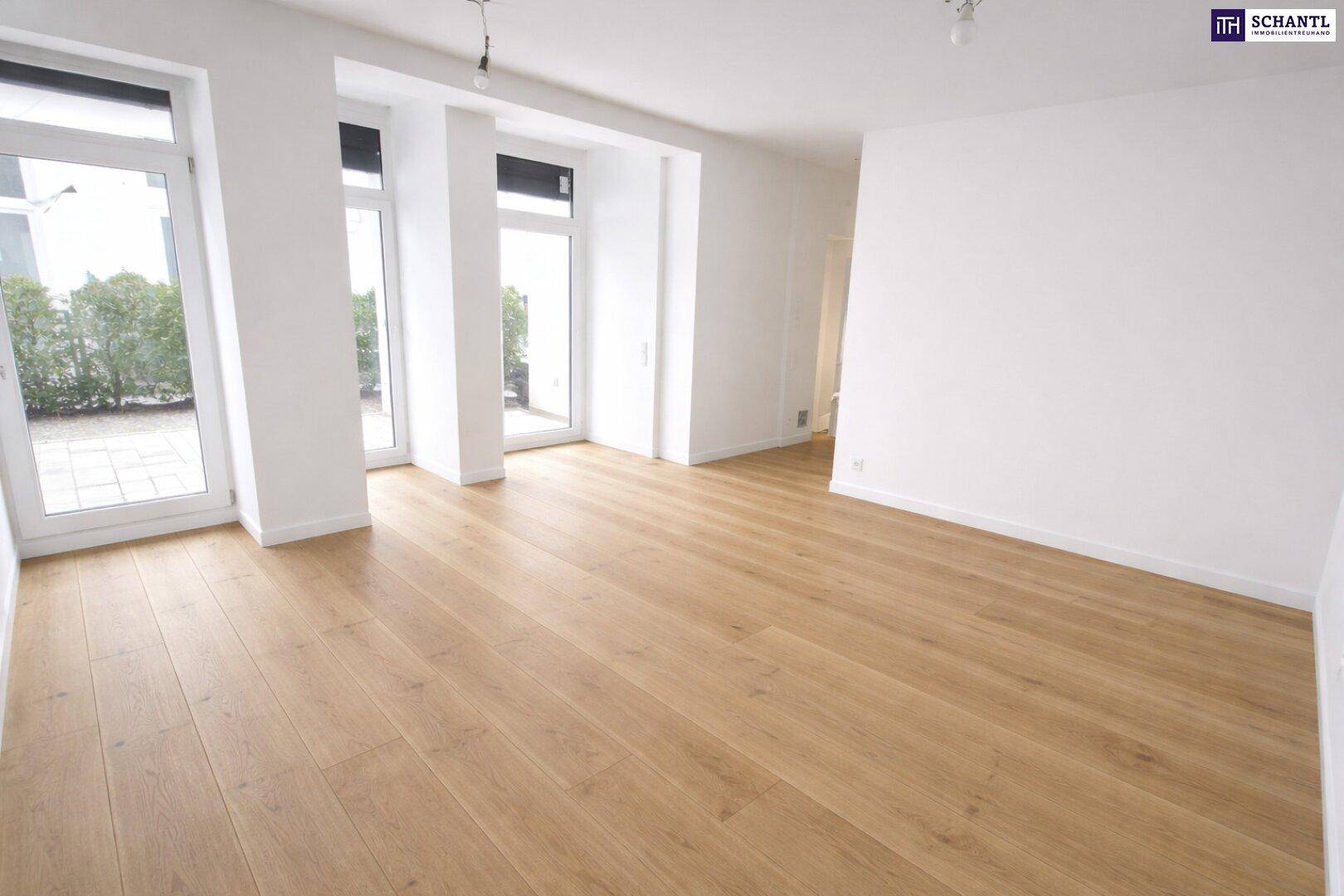 Geräumiges, helles Zimmer mit hellem Holzboden und Zugang zu einem Außenbereich durch Fenstertüren.