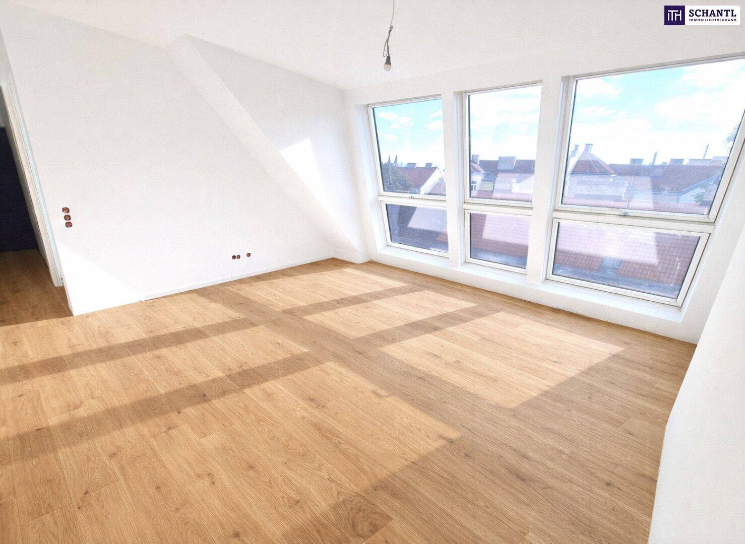 Geräumiger, heller Raum mit Holzboden und großen Fenstern, ideal für einen Wohn- oder Schlafbereich.