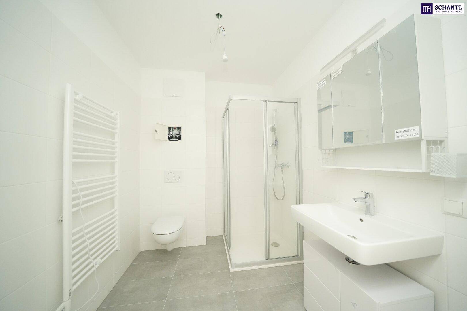Helles Badezimmer mit Duschkabine, wandhängendem WC, Waschbecken und Spiegelschrank.