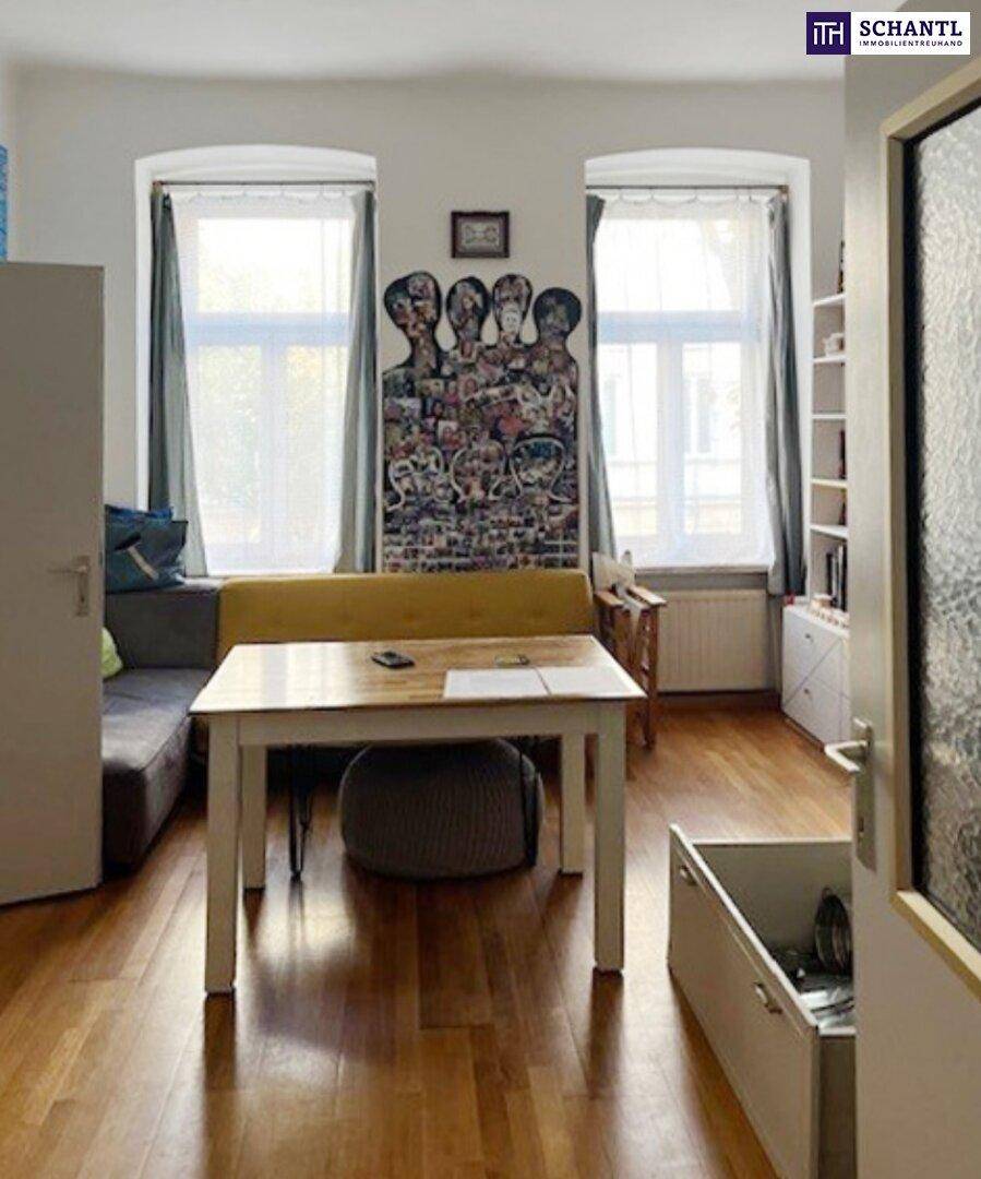 Wohn-Essbereich mit Holzboden, zwei großen Fenstern und moderner Kunst an der Wand.