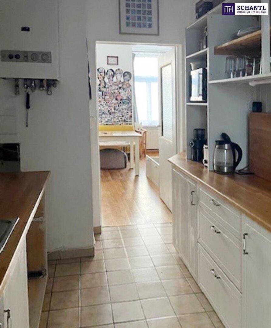 Schmale Küche mit Fliesenboden, Holz-Arbeitsplatten und Blick in einen angrenzenden Essbereich.