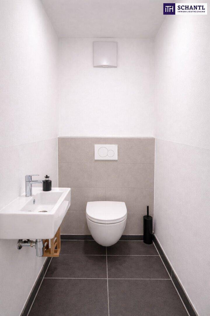 Gäste-WC mit wandhängender Toilette, kleinem Waschbecken und modernen Fliesen.
