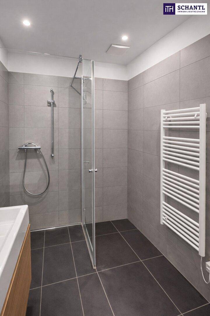 Modernes Badezimmer mit ebenerdiger Dusche, grauen Fliesen und beheiztem Handtuchhalter.