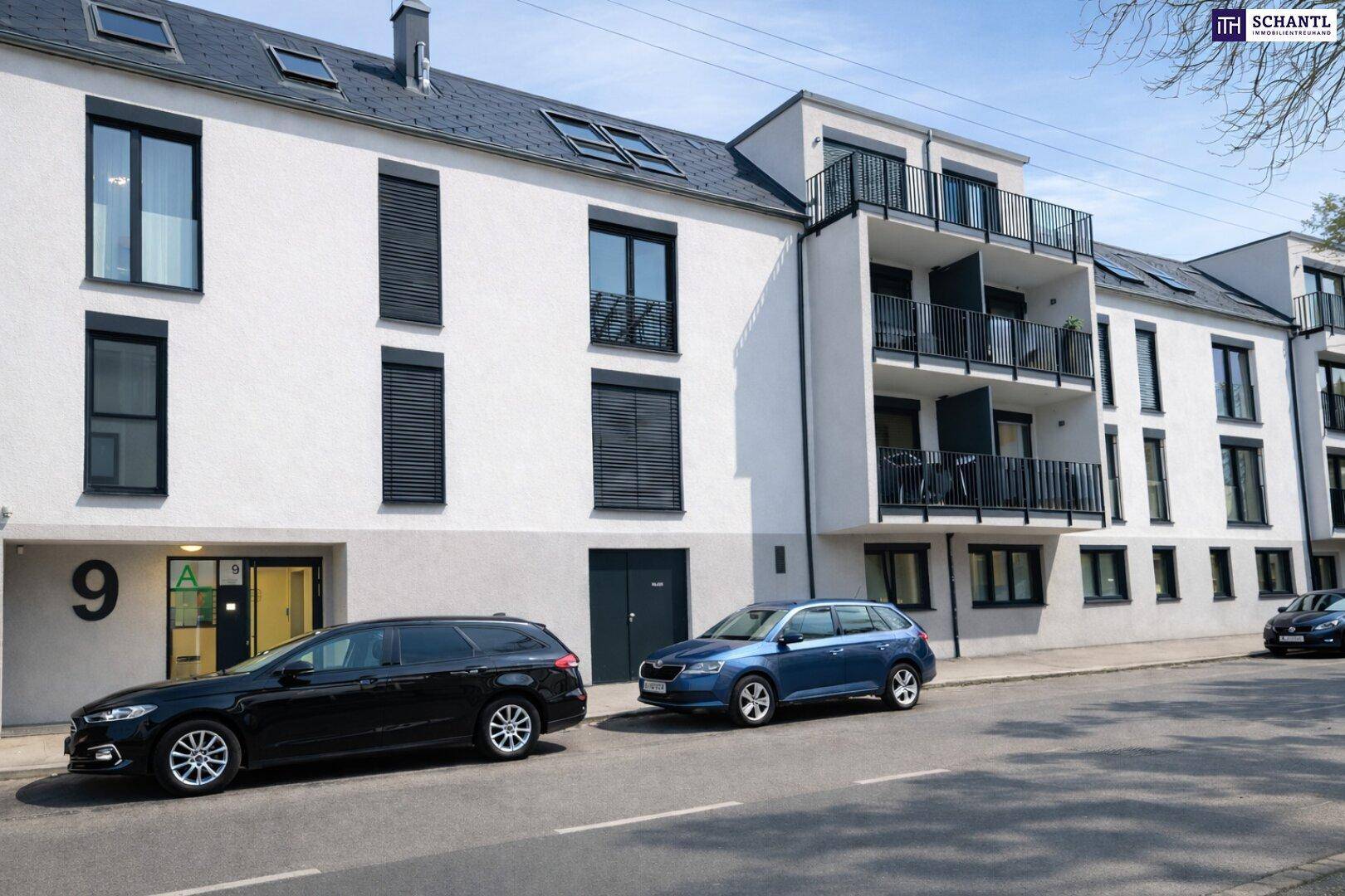 Moderne Wohnanlage mit weißer Fassade, schwarzen Fenstern und Balkonen an einer Straße.