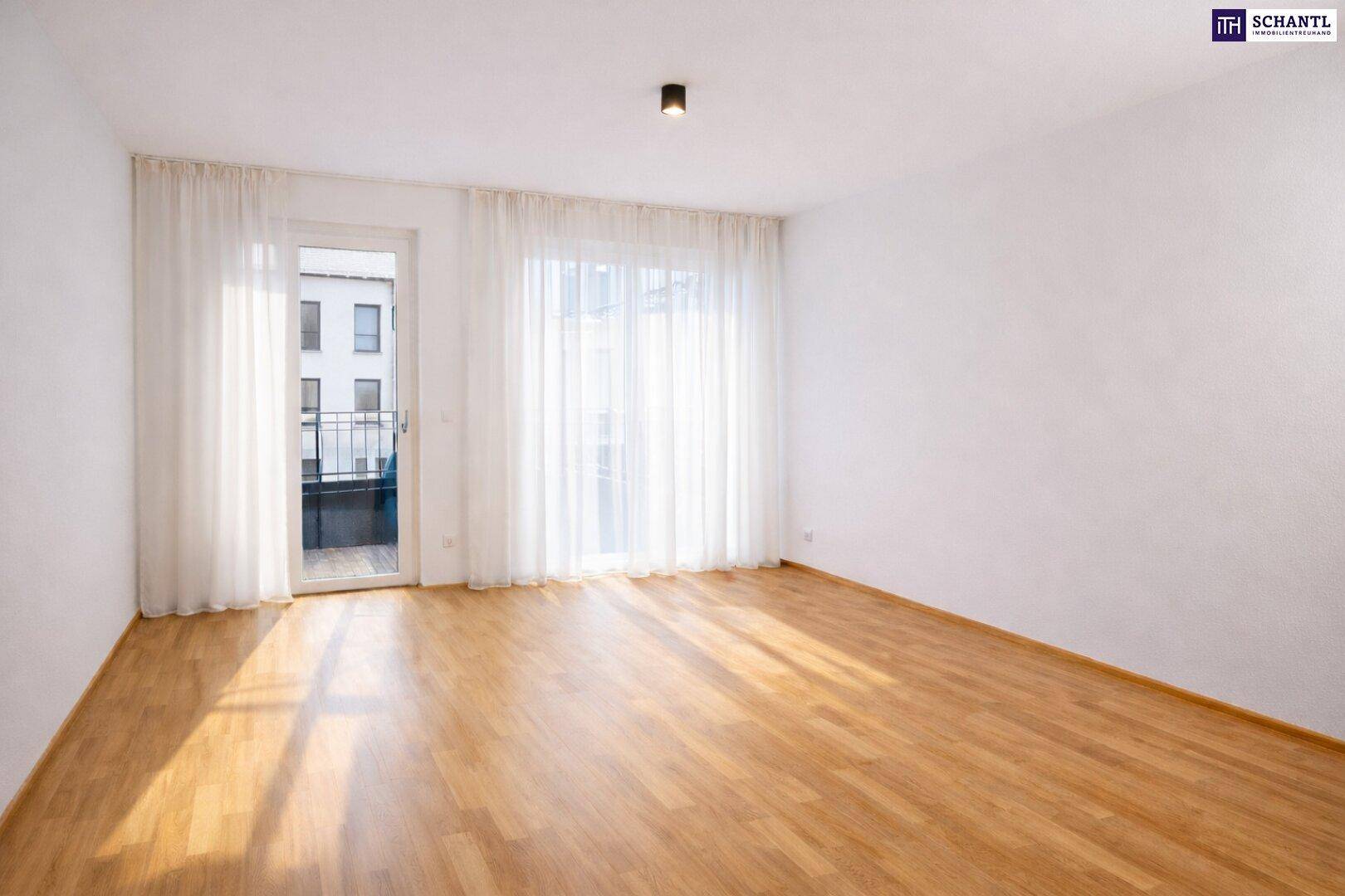 Heller Raum mit Holzboden und Zugang zu einem Balkon, ideal als Wohn- oder Schlafzimmer.