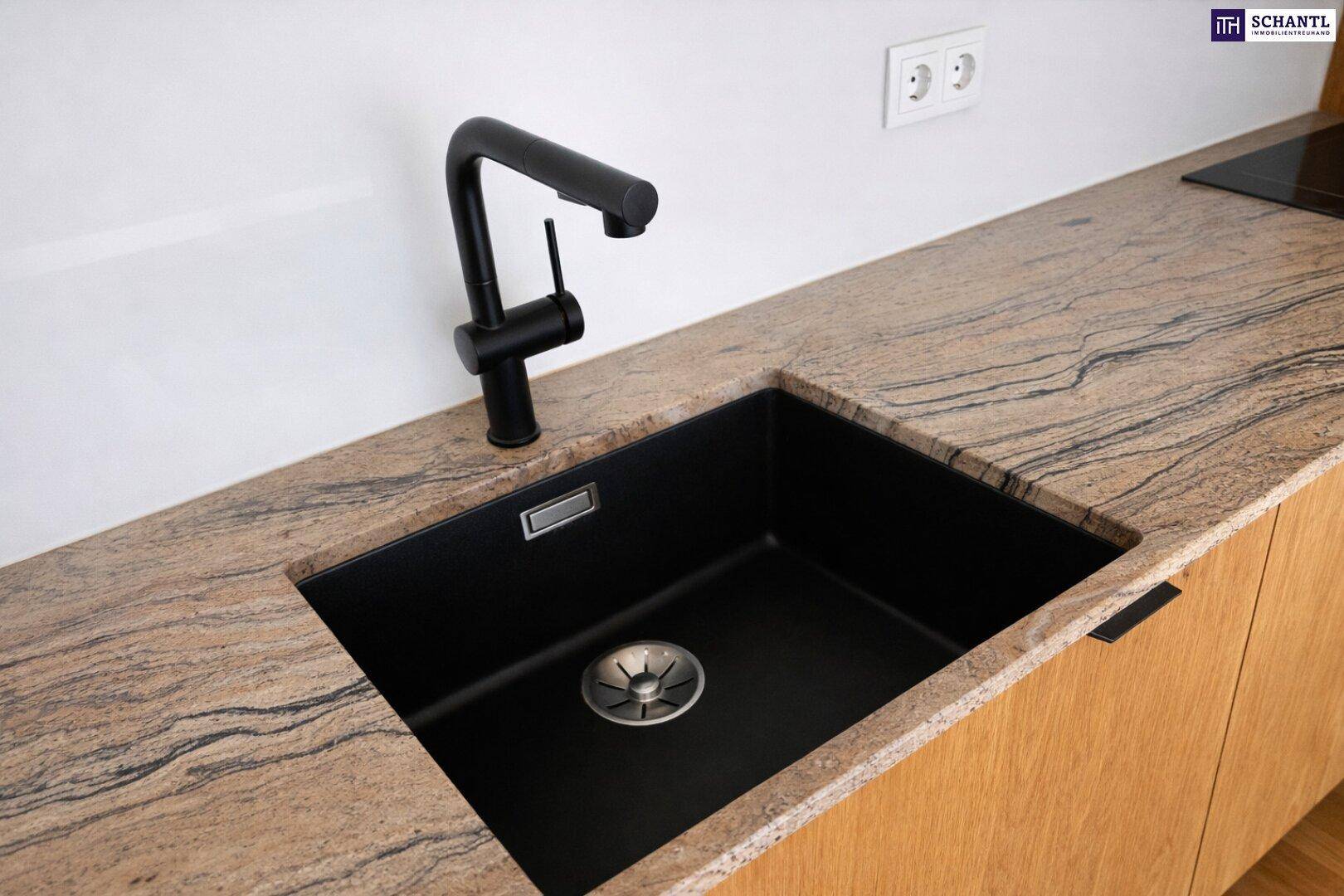 Detailansicht der modernen Küche mit schwarzem Spülbecken, Armatur und gemusterter Granitarbeitsplatte.
