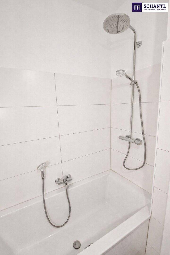 Modernes Badezimmer mit Badewanne, Duscharmatur und weißen Fliesen.