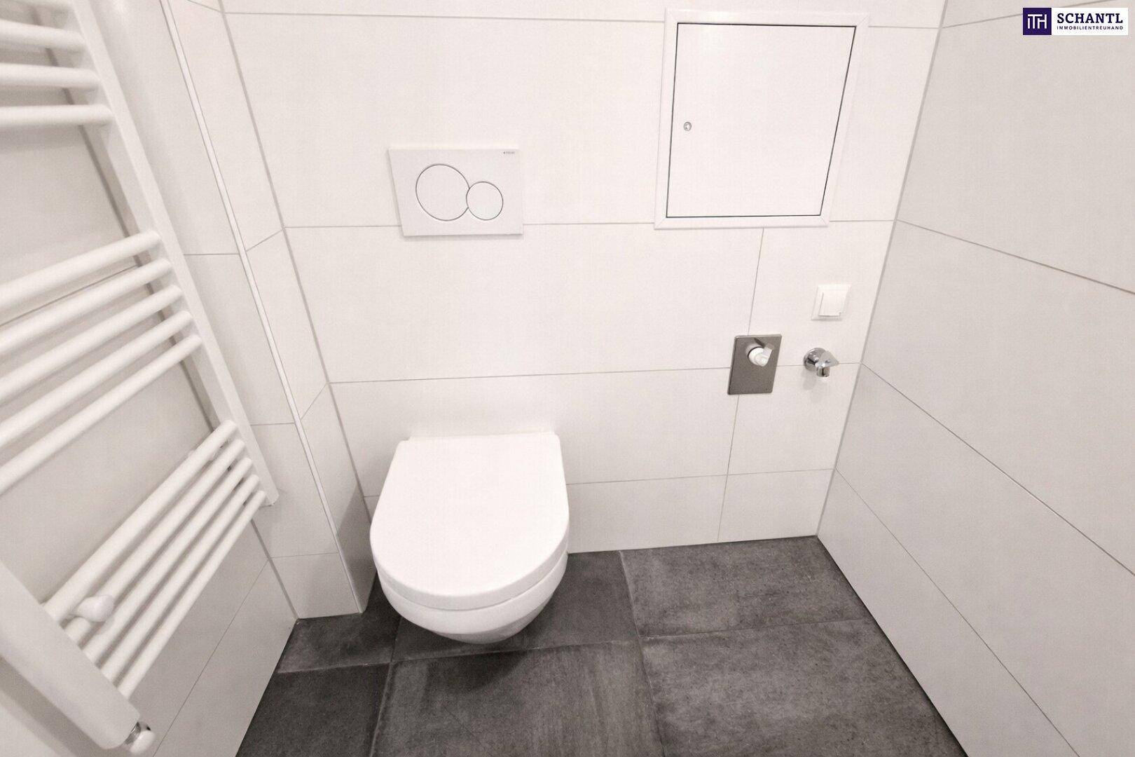 Separates WC mit wandhängender Toilette, dunklem Fliesenboden und Handtuchheizkörper.