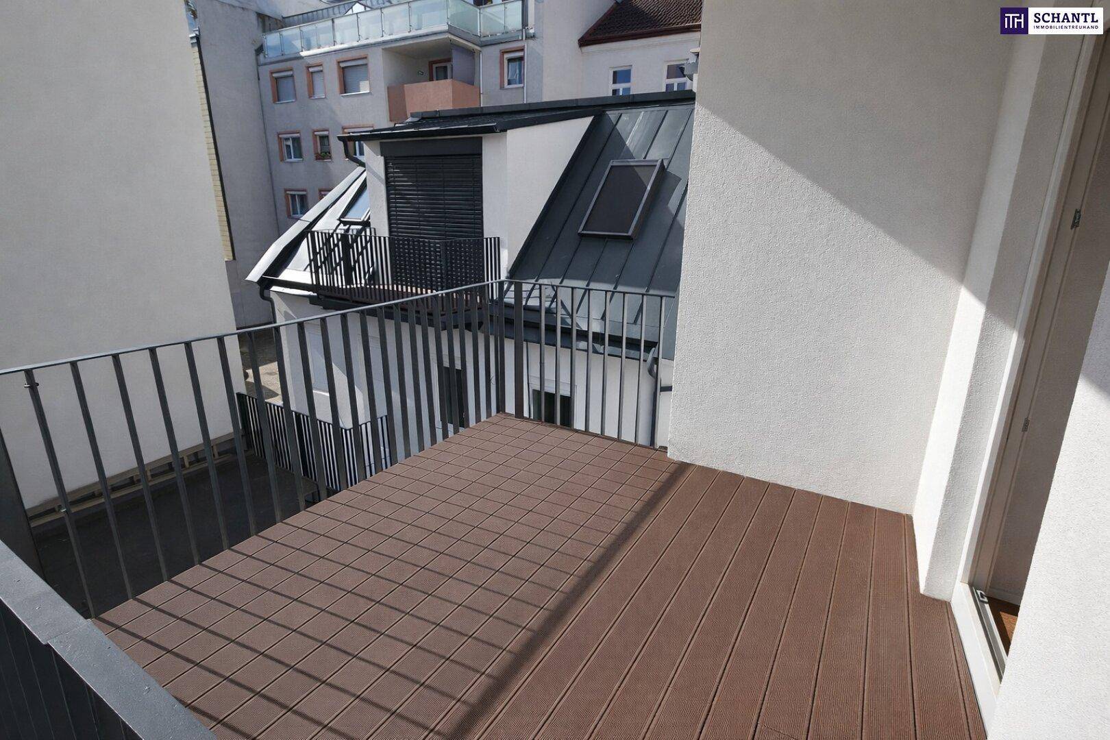 Balkon mit Holzdielen und Metallgeländer, bietet einen Blick auf die umliegenden Gebäude.